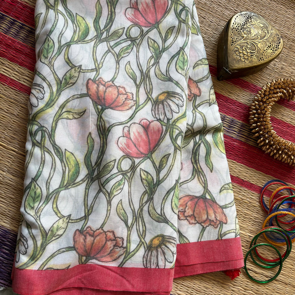White mul cotton with red slub border and botanical prints all over and a tasseled pallu. Comes with a plain white running blouse. 