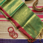 Completely plain tissue by cotton saree in golden and fresh green two tone and red slub border. The pallu has golden tassels.