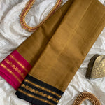 Madhumati is a traditional Gadwal cotton in hazelnut brown with pure silk Ganga-Jamuna borders in pink and black and pure silk palla in pink.
